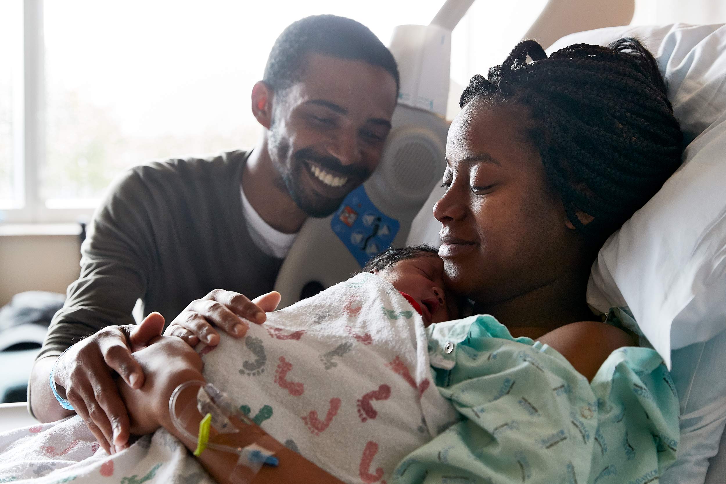 Indoor healthcare photograph of a new family of three in hospital room