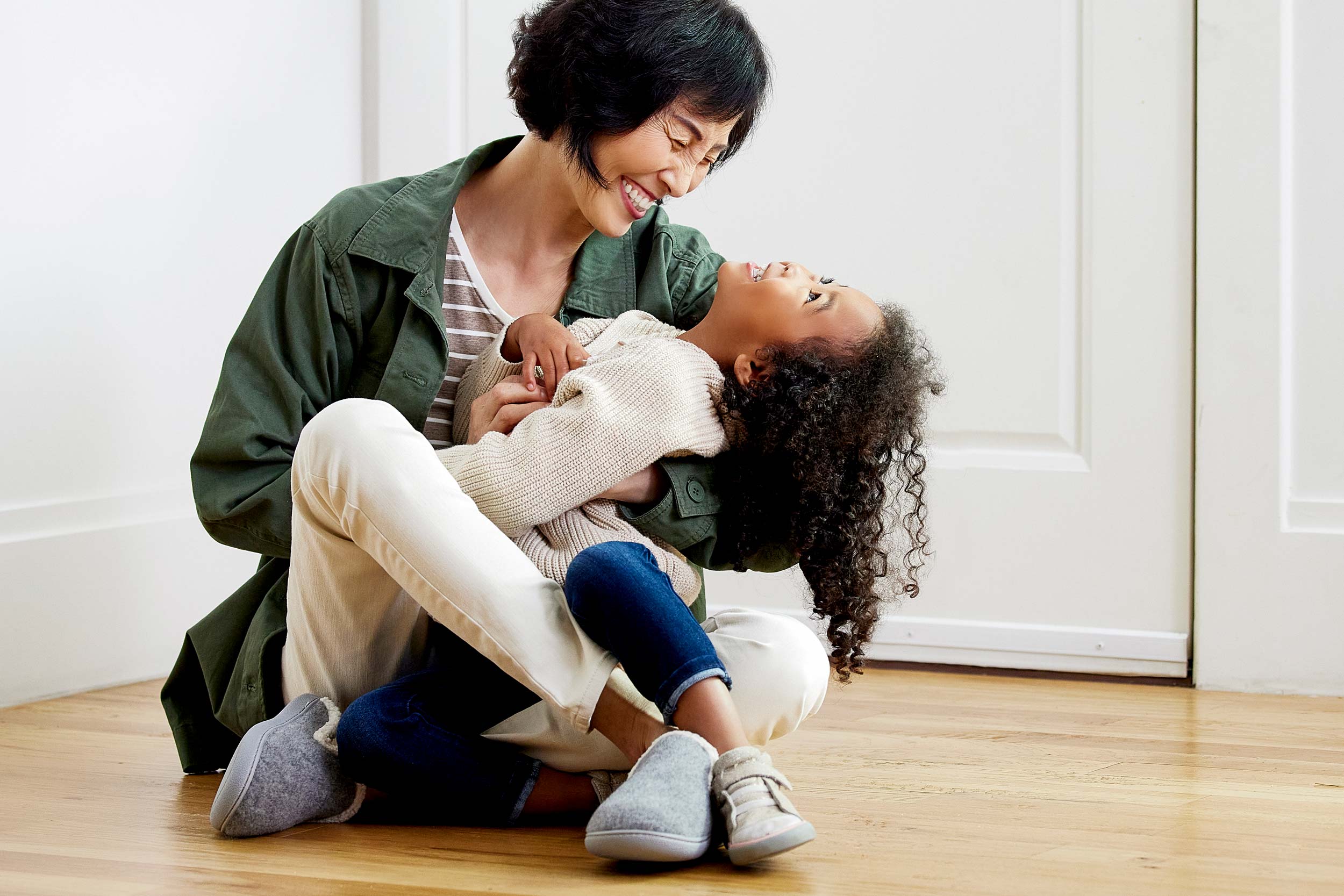 Indoor Lifestyle photograph of a grandmother and granddaughter enjoying time together laughing.