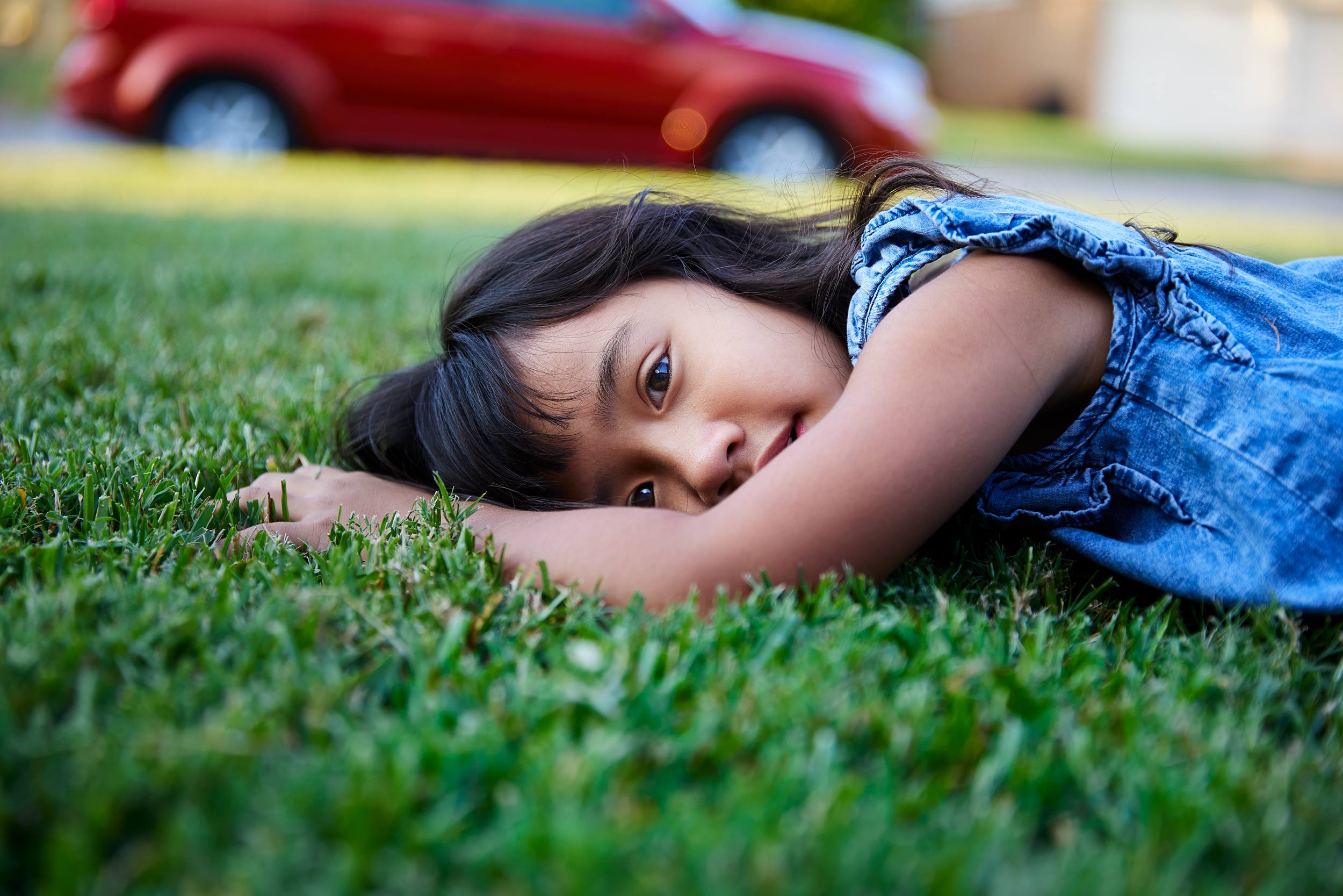 Outdoor lifestyle photograph of a young girl laying in the grass.