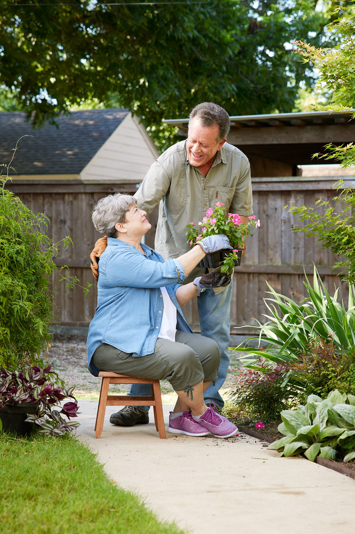 Outdoor lifestyle photograph senior couple gardening planting flowers.