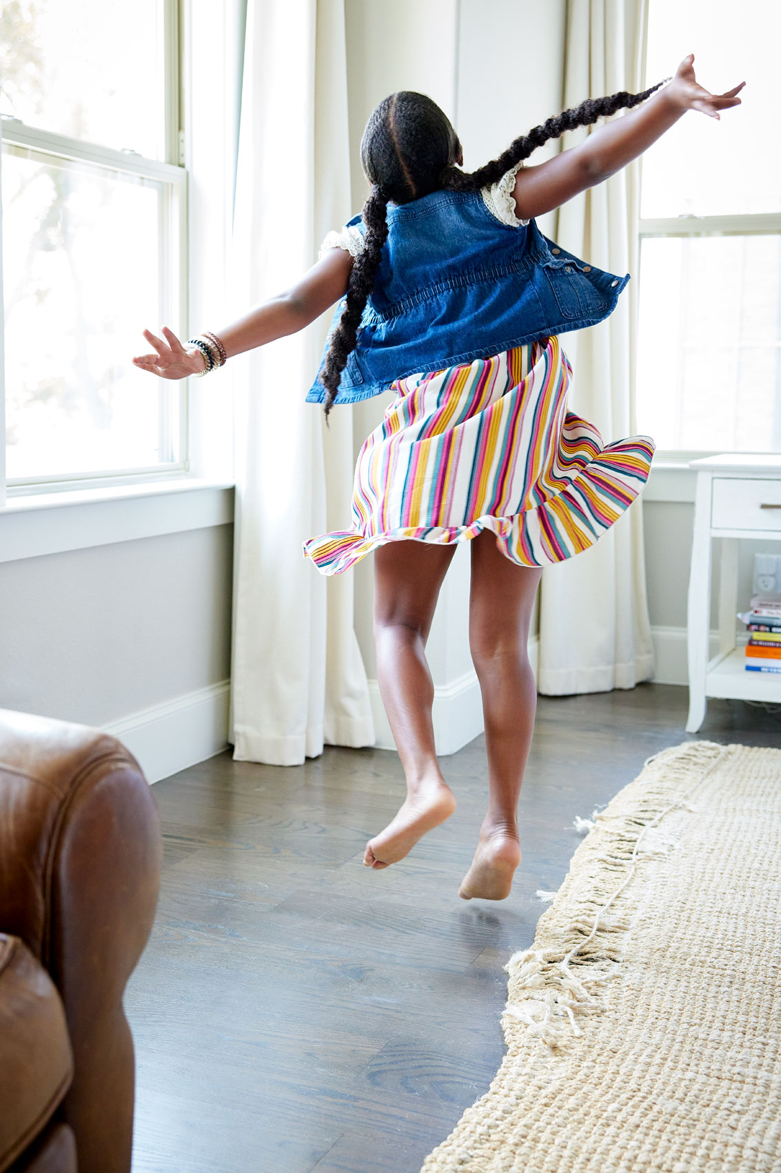 Indoor lifestyle photograph of a young woman dancing in her bedroom.